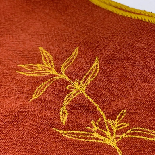Serviette en lin lavé couleur piment, finition dorée_brodée d'une plante aromatique