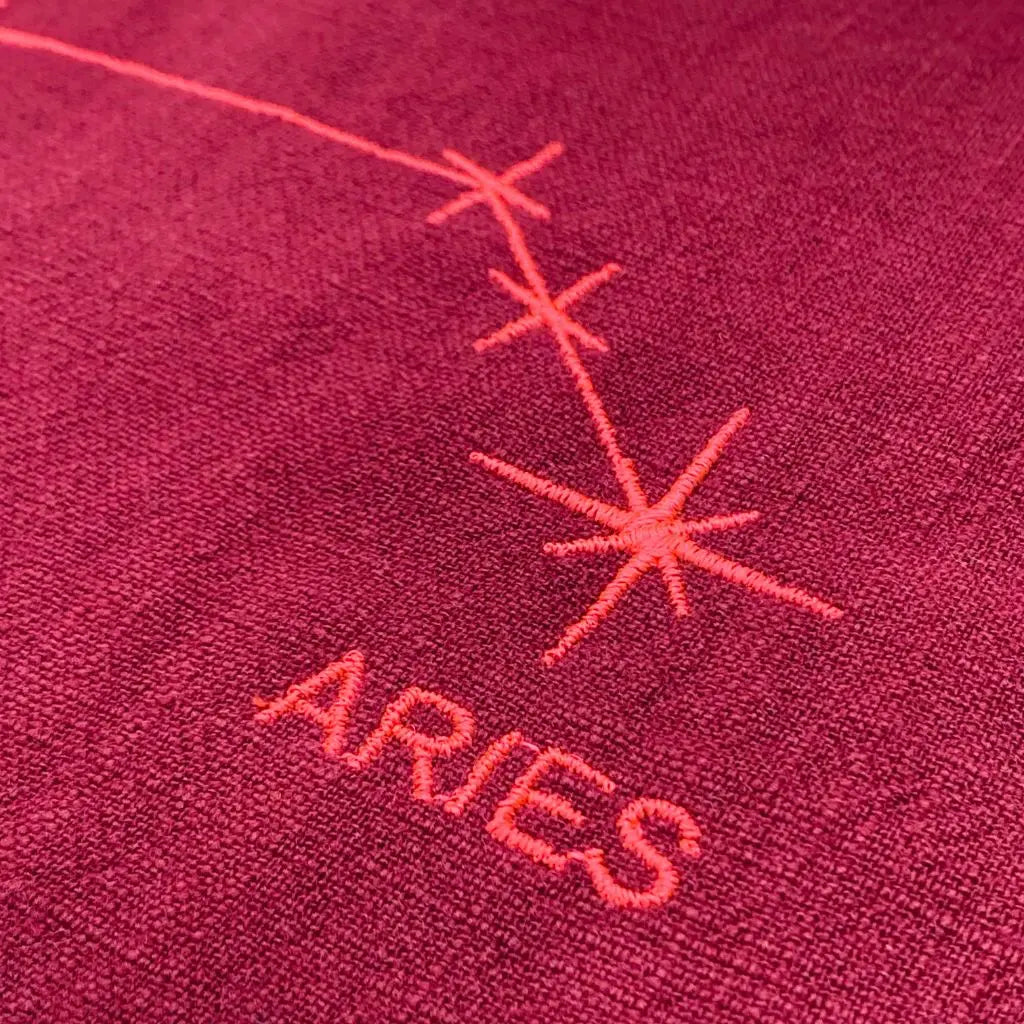 Serviette en lin lavé couleur framboise brodée d'une constellation du zodiaque, relative au signe du bélier. Détail de la broderie.