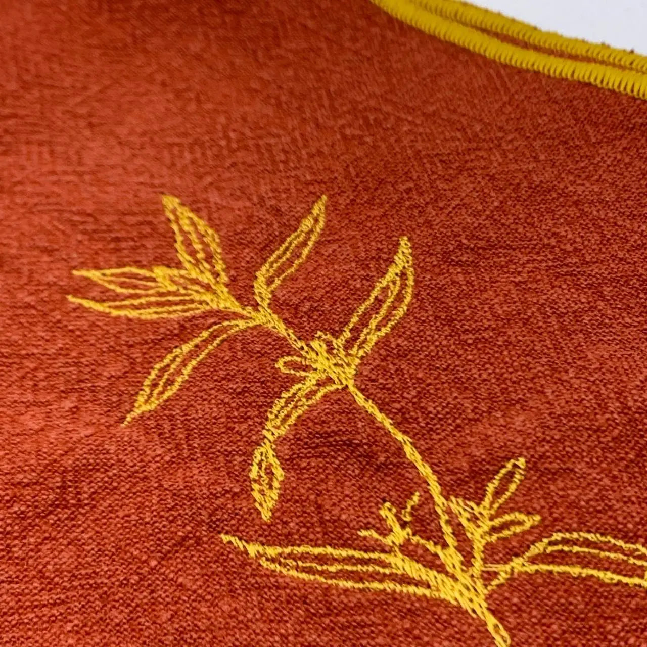 Serviette en lin lavé couleur piment, finition dorée_brodée d'une plante aromatique