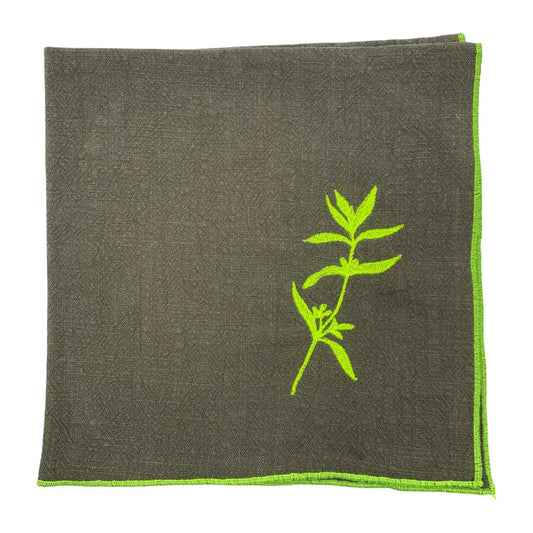 Serviette de table en lin lavé de couleur vert safari, ornée de finitions en jaune néon. Elle présente un motif brodé de sarriette, une plante aromatique. Vue du produit.