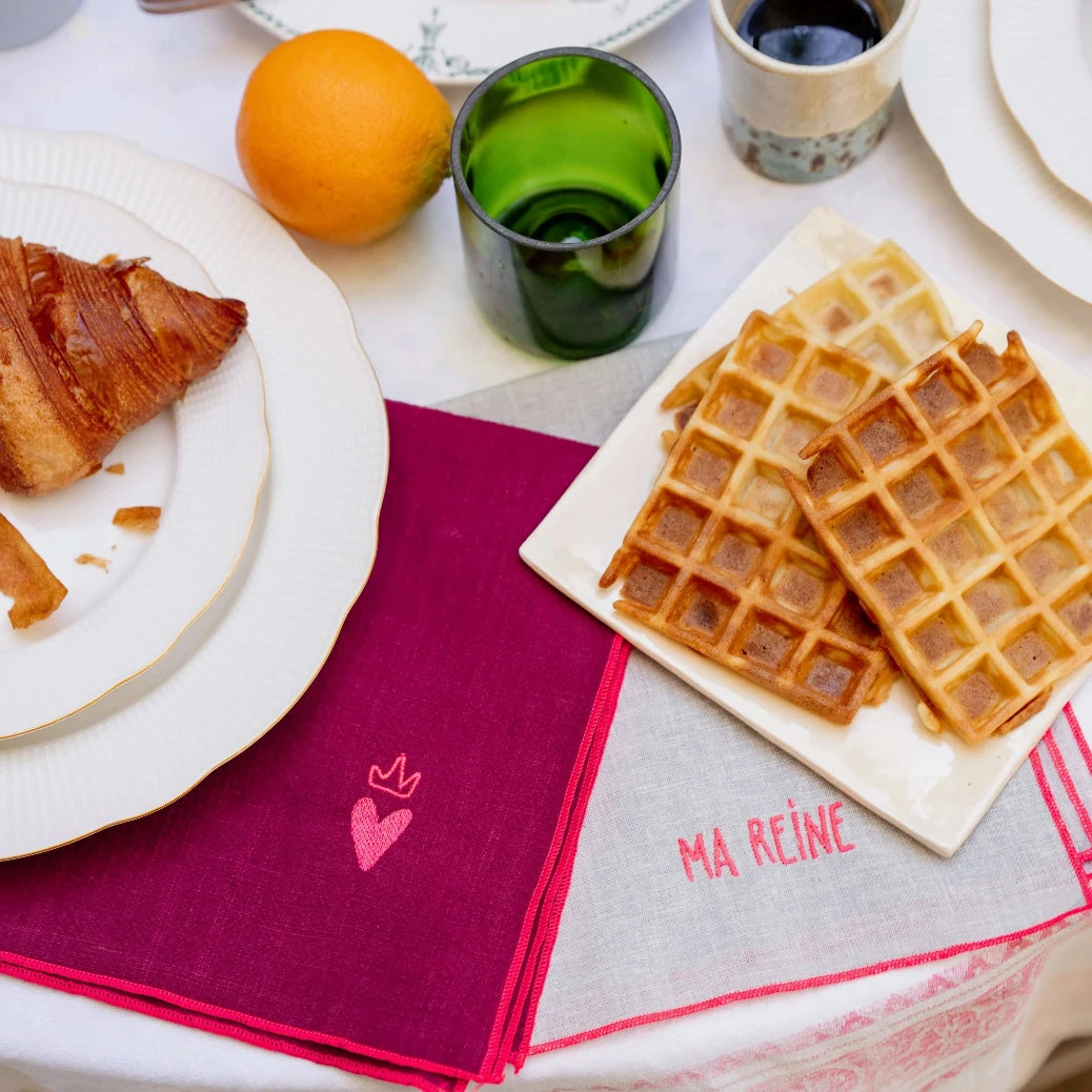 Serviettes de table en lin framboise et grise brodées d'un coeur et l'autre brodé d'un prénom. Vue des produits en situation.