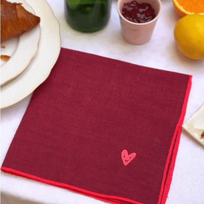 Serviettes de table couleur framboise et grises personnalisées qui s'empilent sur une table.